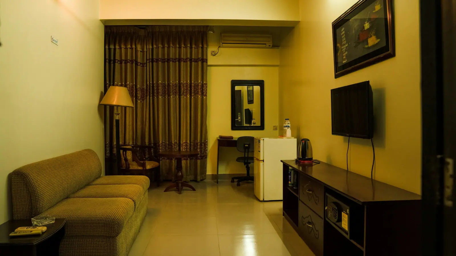 Representative image: a hotel room with a sofa, desk, television and curtains